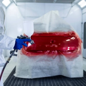 A technician painting a car in red