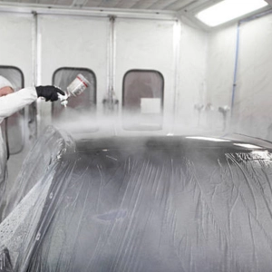 Technician spray painting a car in a professional auto body shop