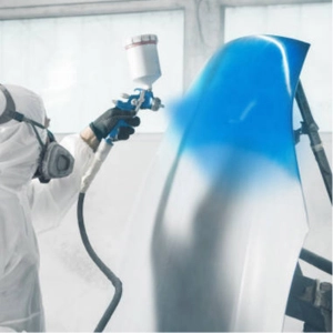 A technician painting a car part in blue