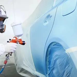 A technician painting a car door and rear panel in blue.