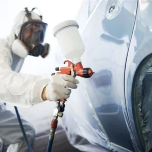 A technician painting a car door in blue