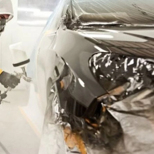 Technician spray painting a car body in a car repair shop